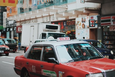 红白相间的出租车在7-Eleven商店标志附近的道路上行驶